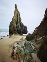 Rock formations on beach against sky