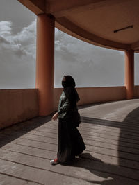 Side view of woman sitting against sky