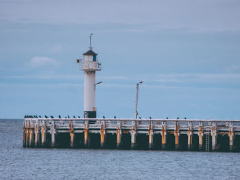 Lighthouse by sea against sky