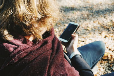High angle view of young man using mobile phone while sitting outdoors