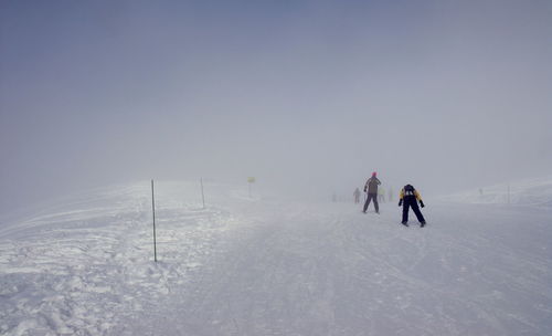 People skiing on landscape against clear sky