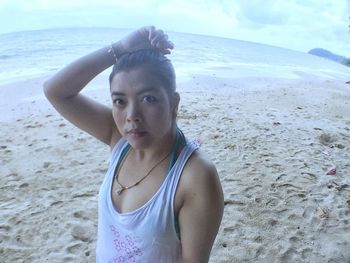 Portrait of young woman on beach against sky