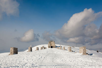 Castle on snowcapped mountain against cloudy sky