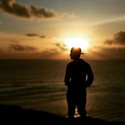 Silhouette man standing on beach against sky during sunset