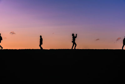 Silhouette people standing against sky during sunset