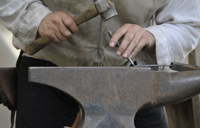 Midsection of man working on metal in workshop
