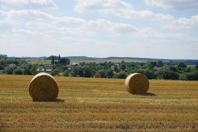 Hay bales on field against sky