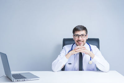 Portrait of man using mobile phone while sitting on table