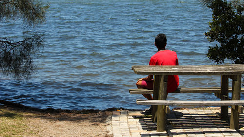 Rear view of man sitting by lake