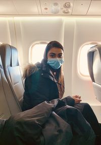 Portrait of woman wearing mask sitting in airplane