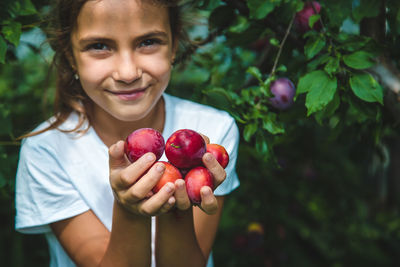 Portrait of girl holding plums in hands