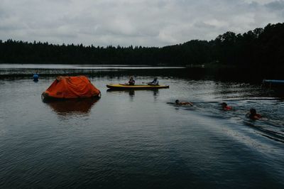 People on lake against sky