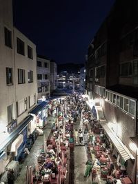 High angle view of illuminated street amidst buildings in city at night