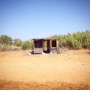 Hut on sand against clear blue sky