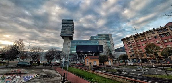 Road by buildings in city against sky