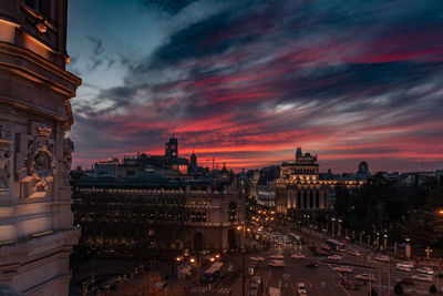 Illuminated buildings in city at sunset