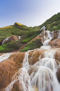 Scenic view of waterfall against sky