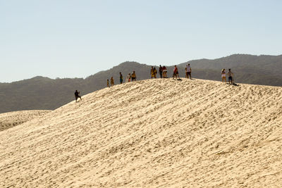 People on sand against clear sky