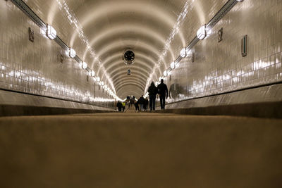 People walking in illuminated tunnel