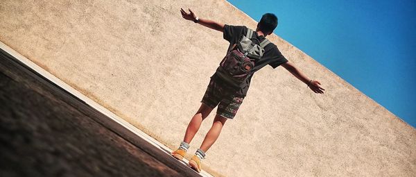 Low angle view of man jumping against clear sky