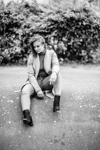 Full length portrait of young woman sitting outdoors