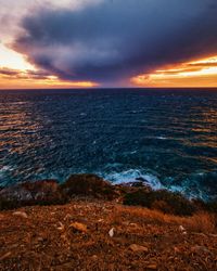 Scenic view of sea against dramatic sky during sunset