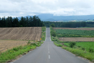 Road amidst field against sky