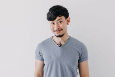 Portrait of young man standing against white background