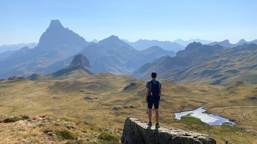 Rear view of man walking on mountain against clear sky