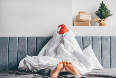 Low section of woman sitting on bed at home