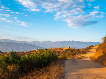 Road amidst plants and mountains against sky