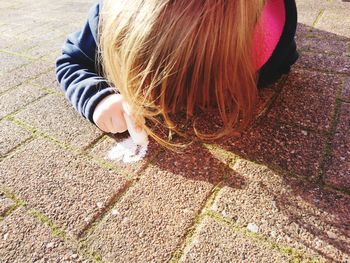 High angle view of woman sitting on footpath