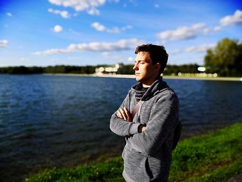 Young man standing against lake during sunny day