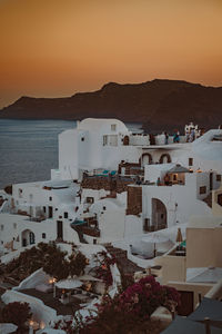 High angle view of townscape by sea against sky during sunset