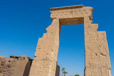 Low angle view of old ruins against clear blue sky
