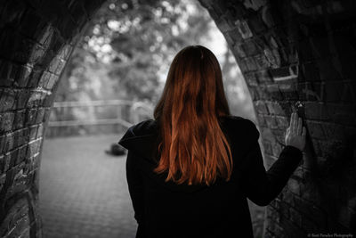 Rear view of woman standing against wall