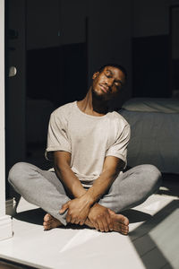 Mid adult man meditating in sunlight at home