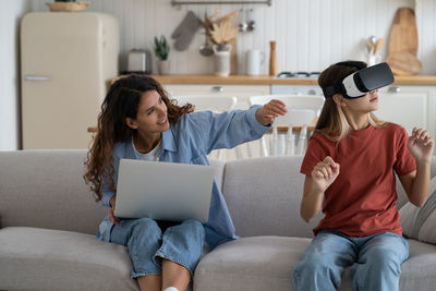 Mother looking at daughter daughter exploring virtual reality a home. families and new technologies