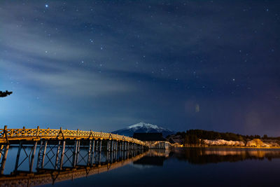 Bridge over river against sky at night