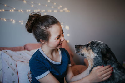 Tween girl playing with her dog on her bed