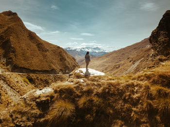 Woman standing on cliff against mountains