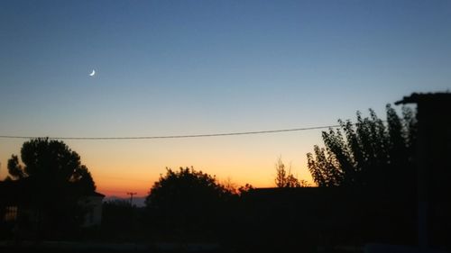 Silhouette trees against clear sky at sunset