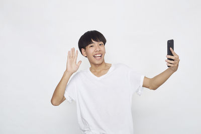 Portrait of smiling young man standing against white background