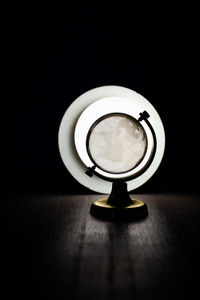 Close-up of illuminated lamp on table against black background