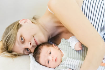 Portrait of mother with baby girl lying on bed