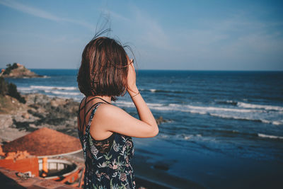 Side view of woman looking at sea against sky