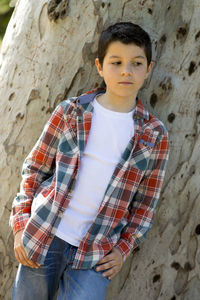 Boy standing against tree