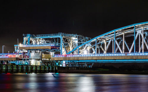 Illuminated bridge over river at night