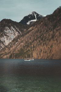 Boat sailing on sea by mountains against sky