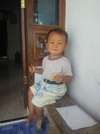Full length of cute baby girl sitting on door at home